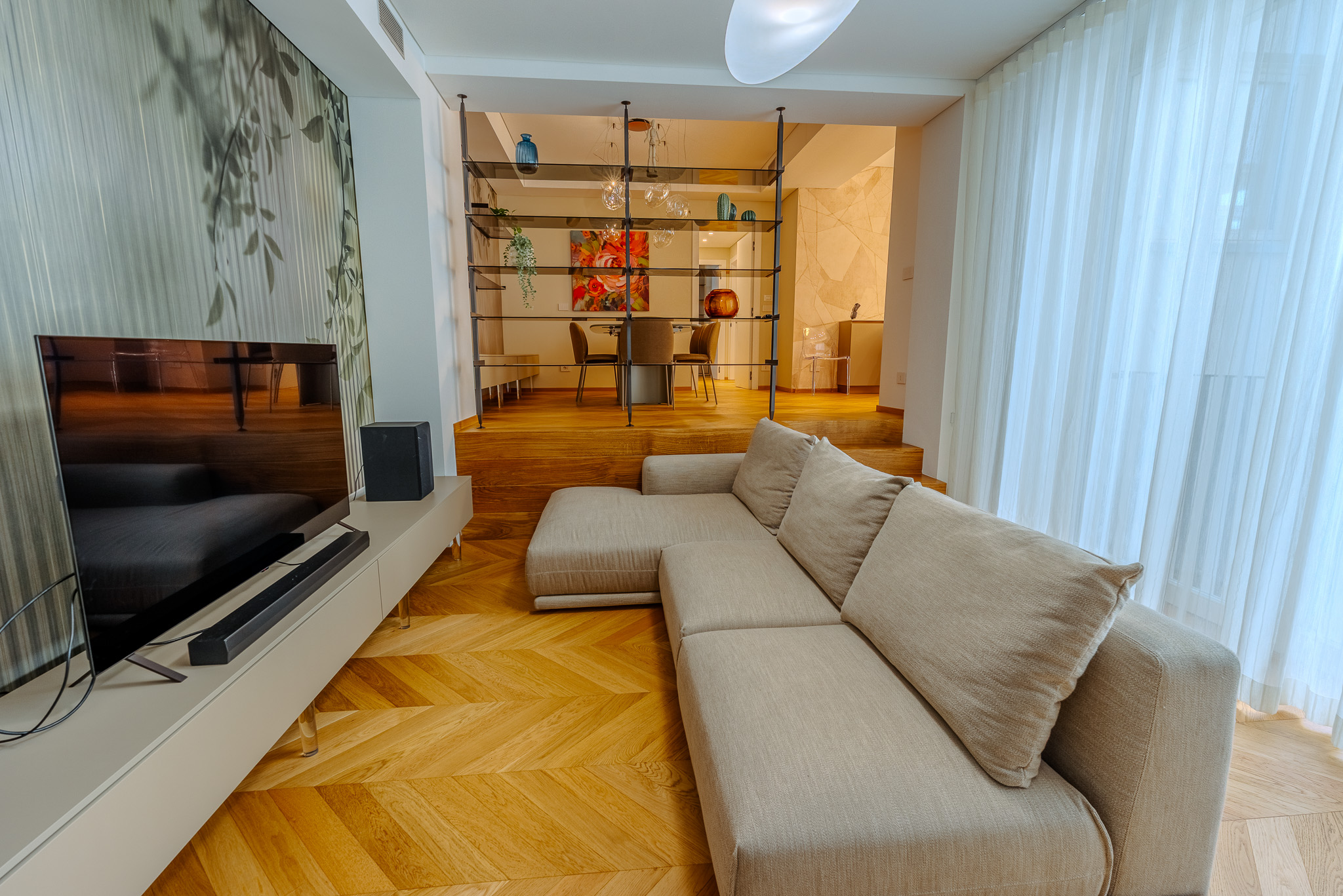 Soggiorno con divano modulare beige e parete a foglie