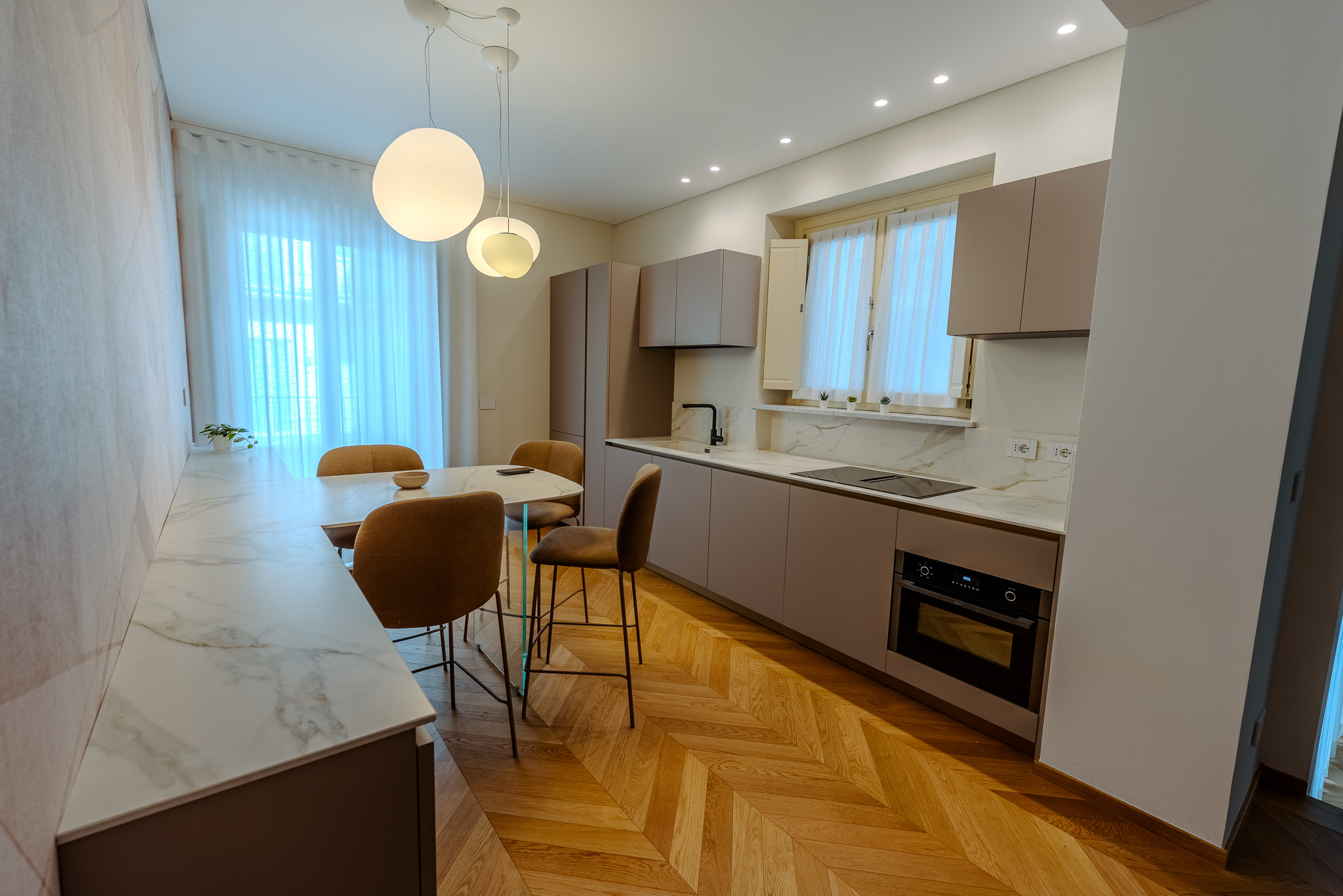 Cucina lineare con top in marmo Calacatta e isola sgabelli