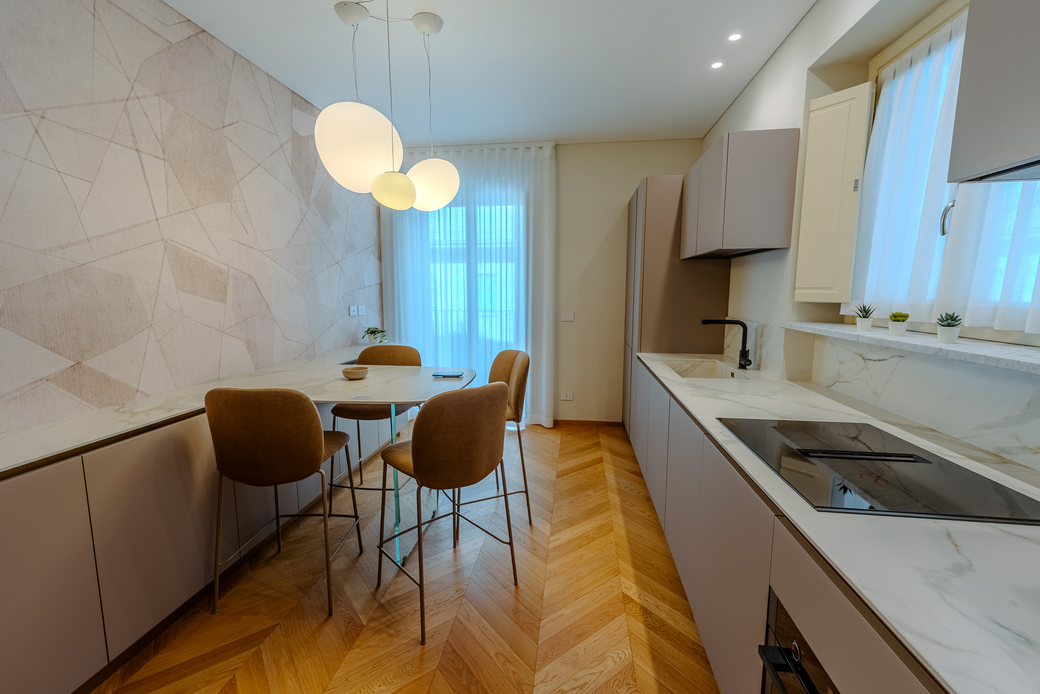 Cucina con isola, sgabelli velluto cammello e lampadari globo