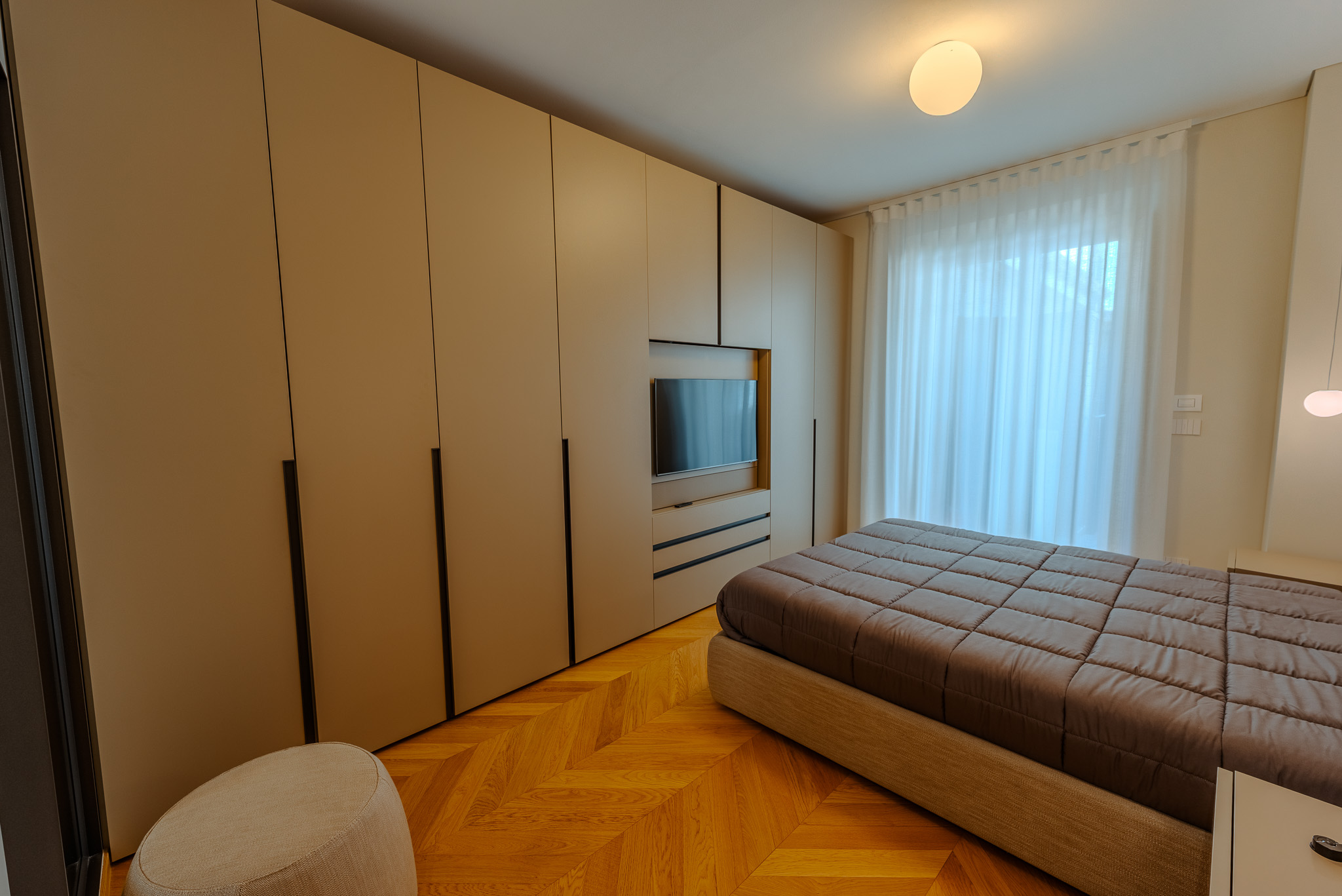 Camera con armadio bianco a parete e TV in nicchia LED
