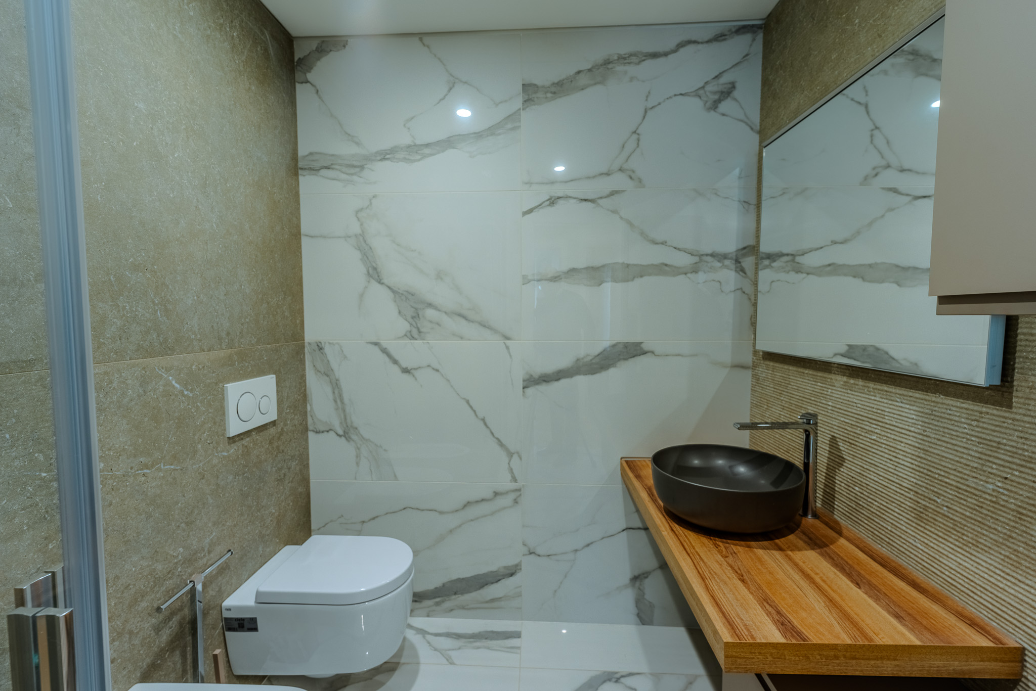 Dettaglio bagno: parete in marmo Calacatta e lavabo nero