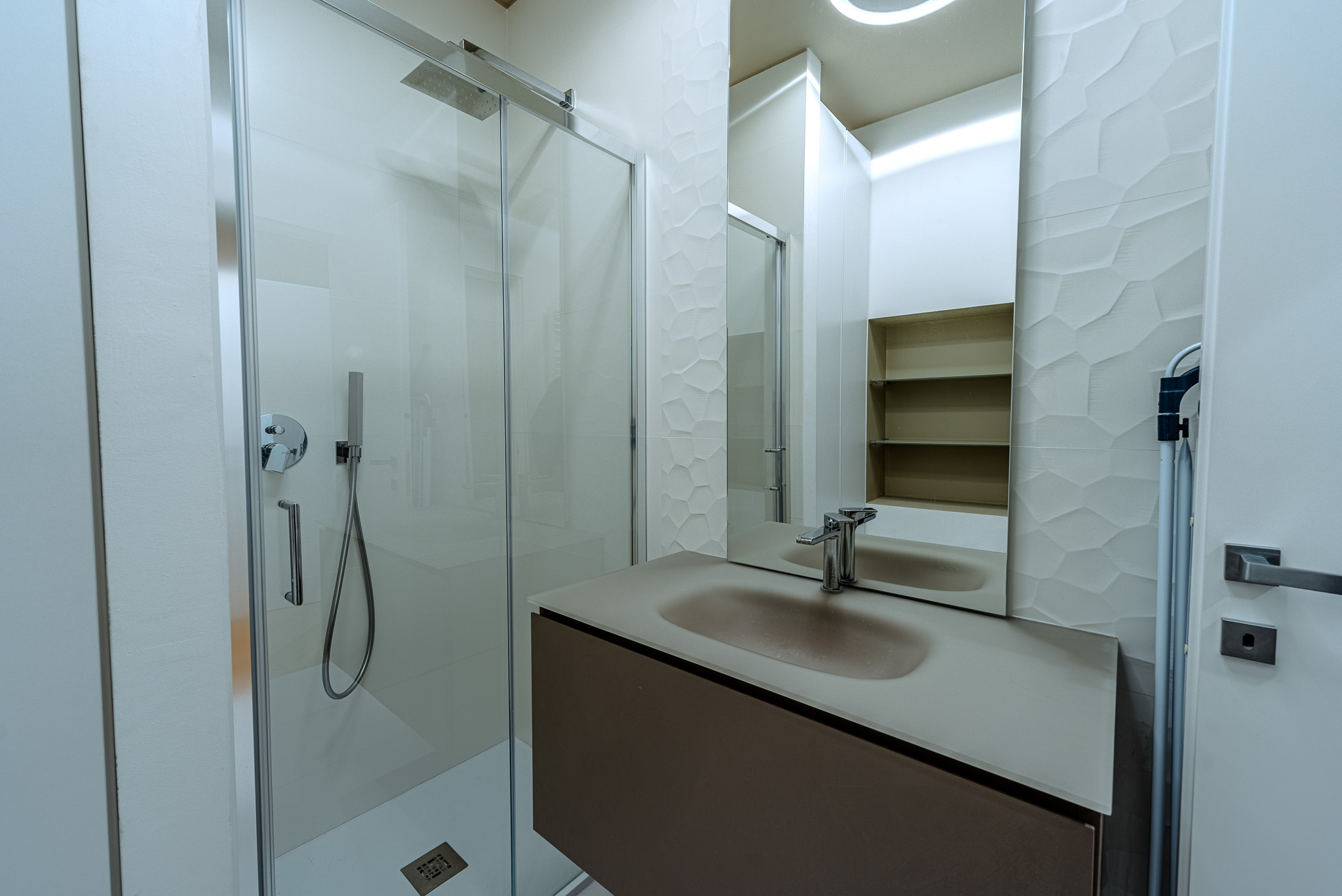 Bagno con doccia walk-in e parete con texture decorativa