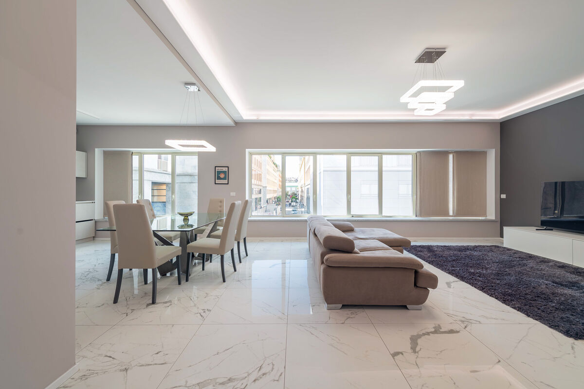 Open-space living with dining table, sofa and marble floors