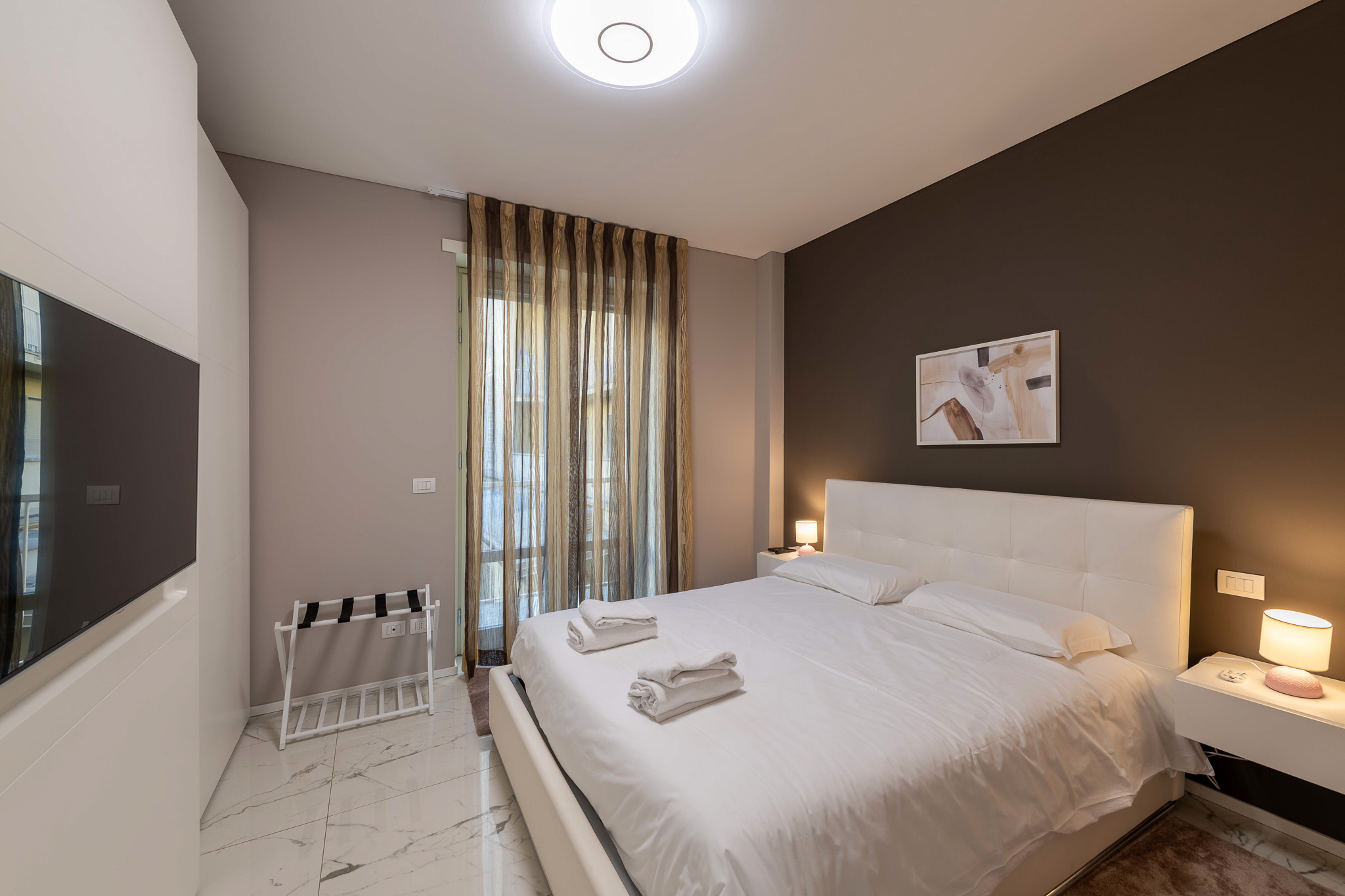 Master bedroom with wall-mounted TV and patterned curtain